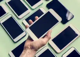 Hand holding a smartphone among a row of phones on display